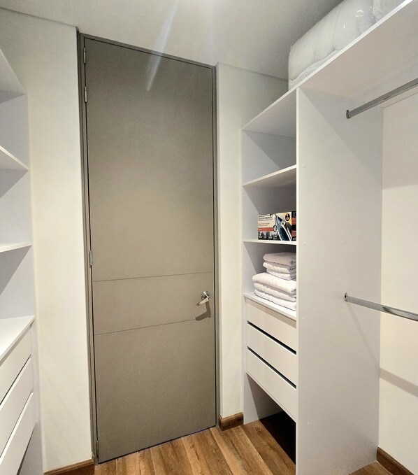 A walk-in closet with a sliding door, open shelving, and a folded towel rack.