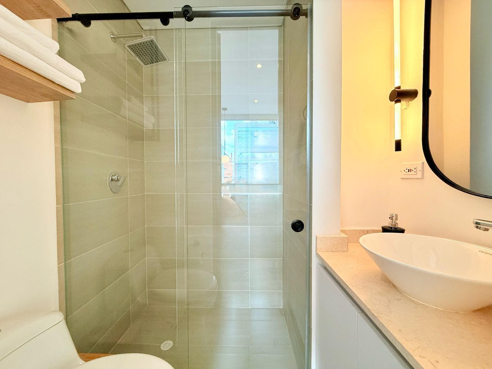 Un baño moderno con cabina de ducha de vidrio, un lavabo blanco y un espejo grande.