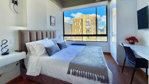 A modern bedroom with a large window, a bed, a bedside table, and a desk. - KD Otoño by Weeki (Bogotá)