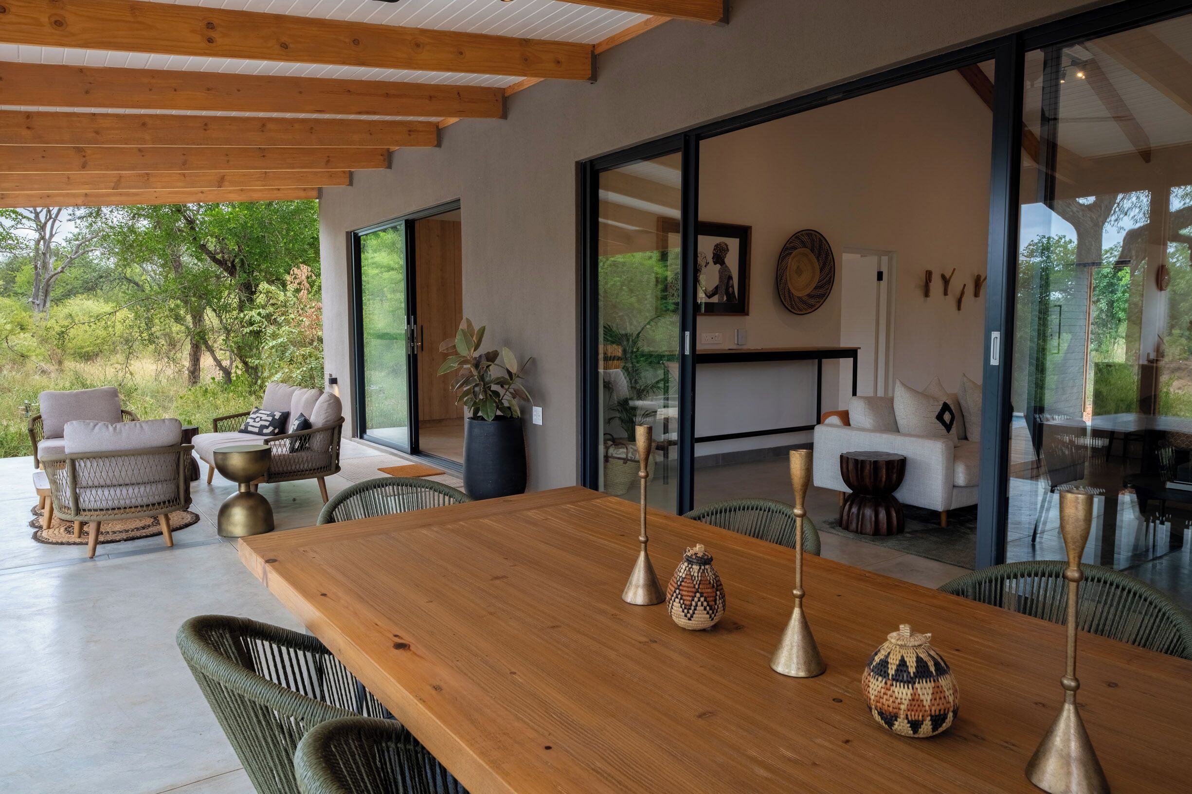 Un comedor moderno con una mesa de madera, sillas de mimbre y un gran ventanal con vistas a zonas verdes.