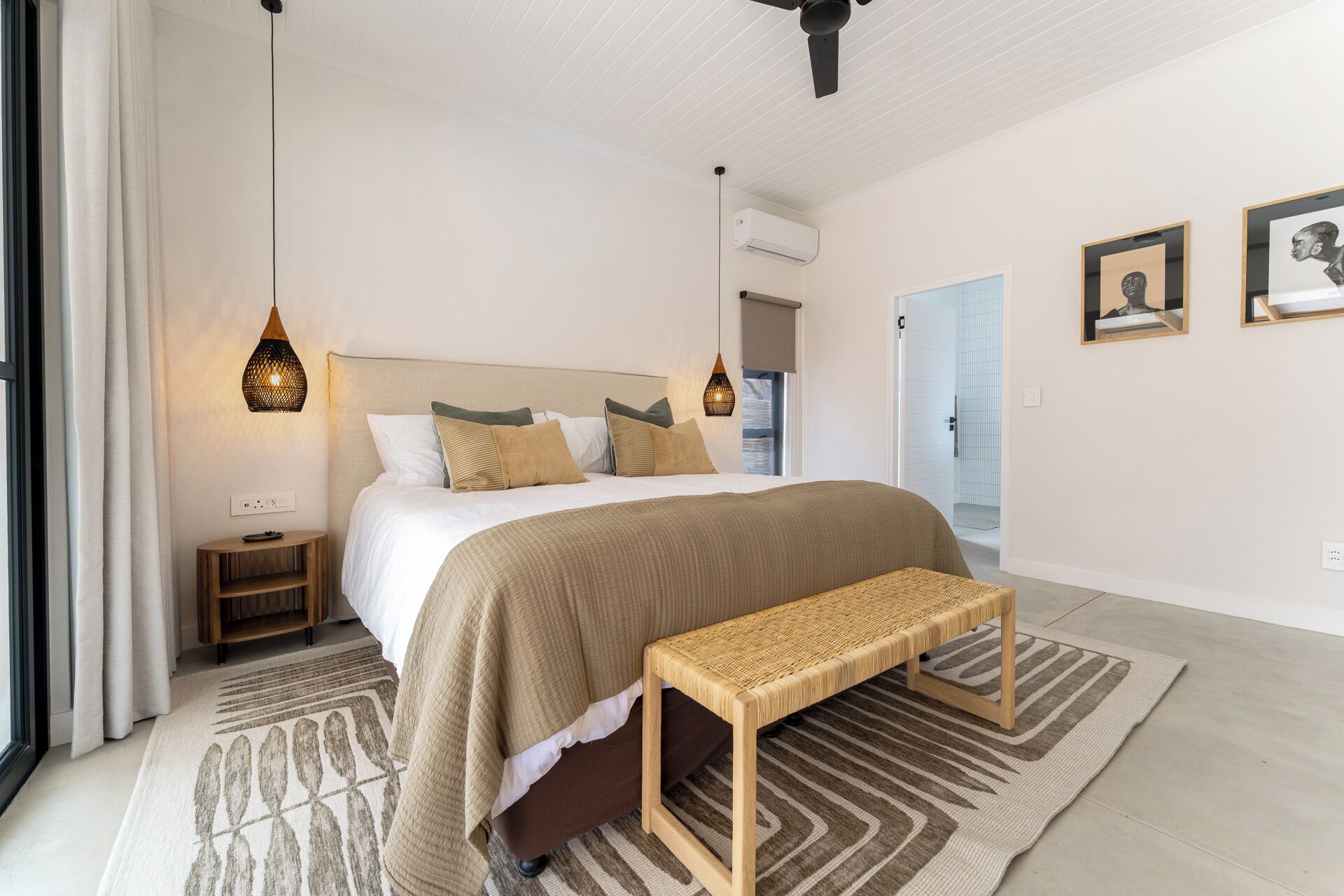 Ein Schlafzimmer mit einem großen Bett, Nachttischen, einer Bank und einem gemusterten Teppich.