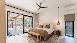 Ein modernes Schlafzimmer mit einem großen Bett, einer Bank und einem Deckenventilator.