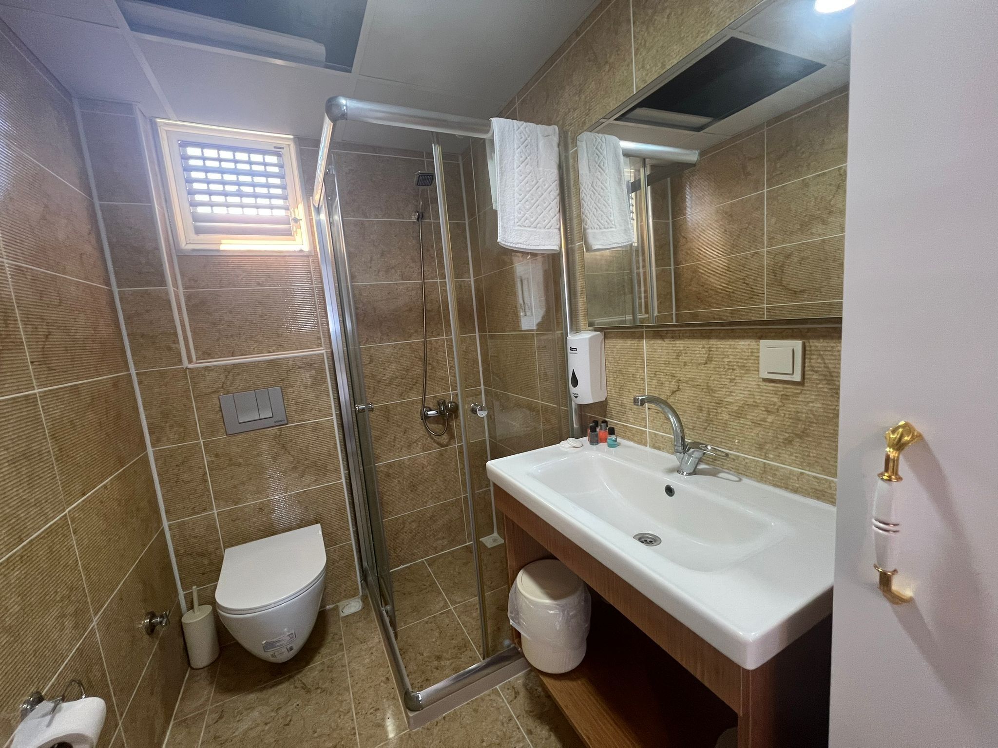 Un baño con ducha de vidrio, lavamanos blanco y un inodoro.