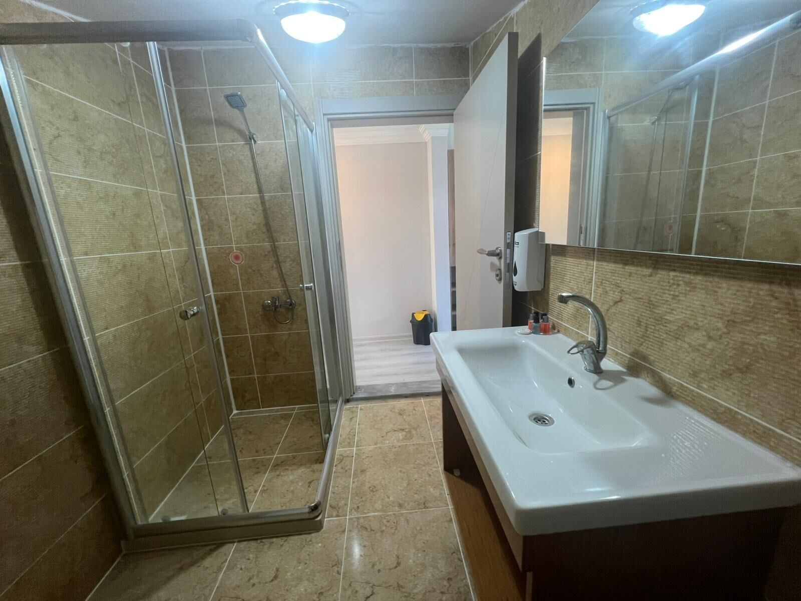 Un baño con ducha envuelta en vidrio, un lavabo blanco y un espejo encima.