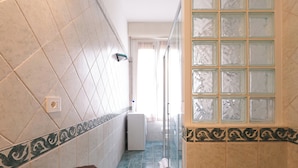 Une salle de bain avec une douche, un porte-serviettes et une plante en pot.