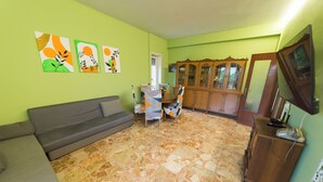 A living room with a sofa, a dining table with chairs, a cabinet, and artwork on the wall. - Raffaele's apartment, Tranquility and comfort, Suitable for small groups and families (Roma)