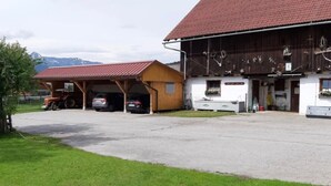 A rural property with a barn, covered parking area, and a white building with a red roof. - Holiday Home 'Landlhof' with Mountain View, Private Terrace and Wi-Fi (Ramsau)