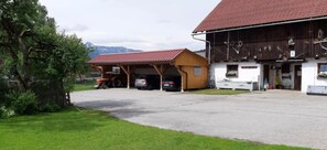 A rural property with a barn, covered parking area, and a white building with a red roof.