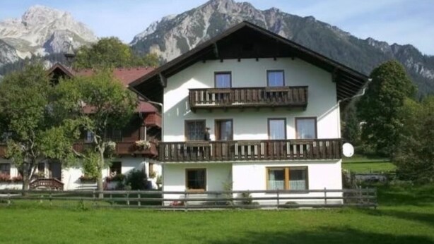 A two-story building with balconies, surrounded by mountains. - Holiday Home 'Landlhof' with Mountain View, Private Terrace and Wi-Fi (Ramsau)