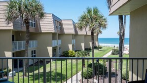 Ein Wohngebäude mit Balkon mit Blick auf Strand und Meer.