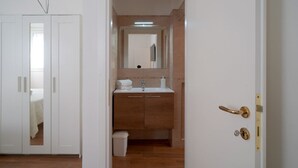 A bathroom with a white sink, a mirror, and a door with a brass handle.