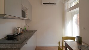 A compact kitchen with a built-in microwave, a kettle, and a coffee maker on the counter.