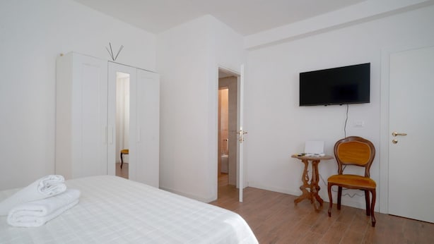 A hotel room with a bed, a television, a wooden chair, and a small table.