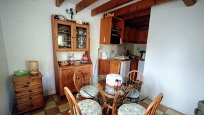 A dining area with a glass table surrounded by wicker chairs, wooden cabinets with glass doors, and a tiled floor. - House in lovely gardens with shared pool in Dordogne, parking on site (Bouteilles Saint-Sébastien)