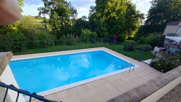 A rectangular swimming pool with a metal ladder on one side, surrounded by a fence and a grassy area with trees. - House in lovely gardens with shared pool in Dordogne, parking on site (Bouteilles Saint-Sébastien)
