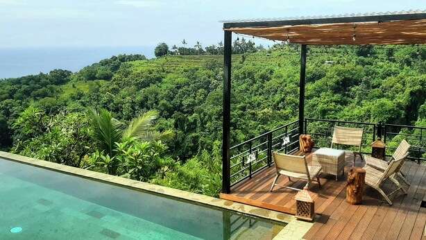 A rooftop infinity pool with a wooden deck and outdoor seating area overlooking a lush green landscape and the ocean. - LiRi Villa - Private villa with Magnificent ocean, jungle, valley view (Bali)
