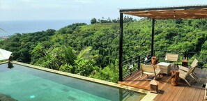 A rooftop infinity pool with a wooden deck and outdoor seating area overlooking a lush green landscape and the ocean. - LiRi Villa - Private villa with Magnificent ocean, jungle, valley view (Bali)
