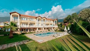 A large hotel with multiple balconies, a swimming pool, and lush greenery. - NG Hisar Apart (Fethiye)