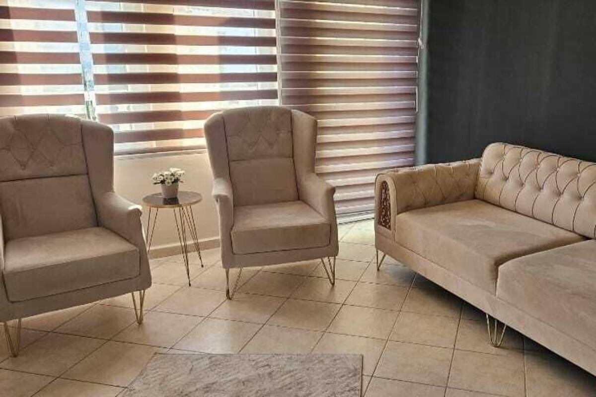 A living room with two armchairs, a sofa, and a small table with a plant.