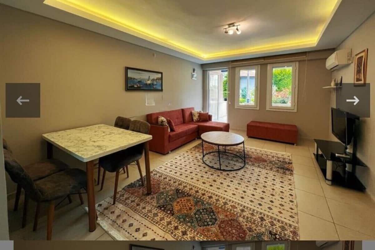A living room with a sofa, a coffee table, a TV, and a dining area with a table and chairs.