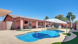 A backyard with a swimming pool, a covered patio, and a brick house. - Near Golf Courses: Poolside Paradise in Yuma! (Yuma)