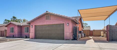 A residential area with a pink house, a garage, and a covered patio area.