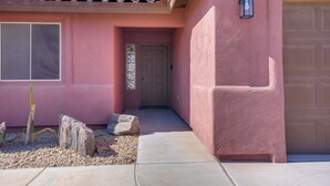A house with a pink exterior, a front door, a garage door, and a small cactus in the front yard. - Near Golf Courses: Poolside Paradise in Yuma! (Yuma)