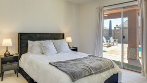 A bedroom with a bed, two bedside lamps, a nightstand, and a view of an outdoor patio. - Near Golf Courses: Poolside Paradise in Yuma! (Yuma)