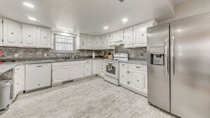 A modern kitchen with white cabinetry, a stainless steel refrigerator, and a built-in oven. - 4 Mi to Museums: Roswell Getaway w/ Game Room! (Roswell)