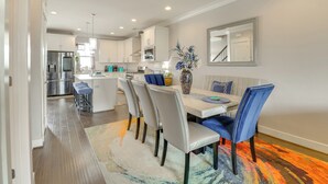 A modern kitchen with white cabinets, stainless steel appliances, and a central island. - Walk to Ocean: Group Getaway in Virginia Beach! (Virginia Beach)