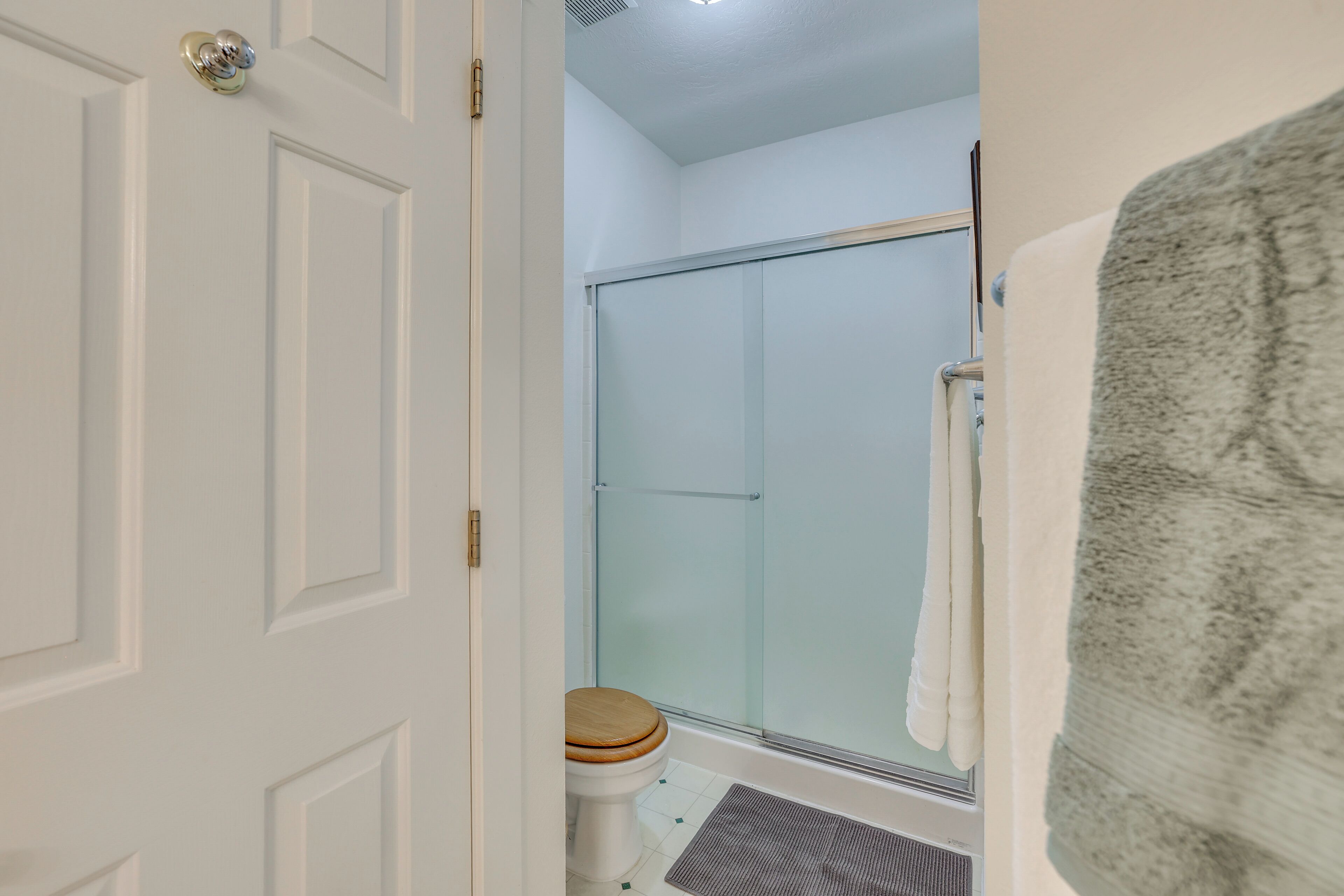 A bathroom with a glass shower enclosure, a toilet, and a towel rack.