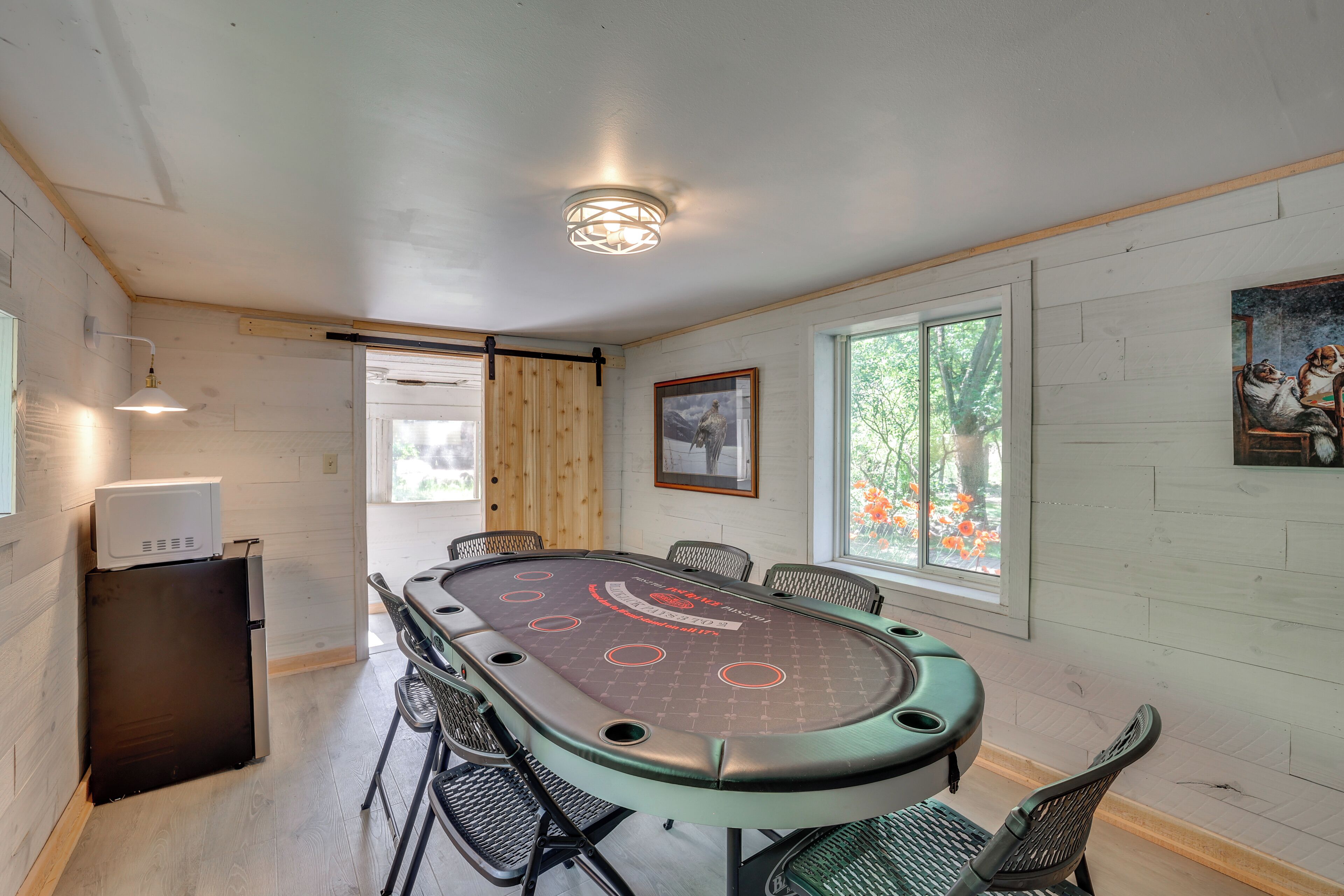 A conference room with a table, chairs, a refrigerator, and a painting on the wall.