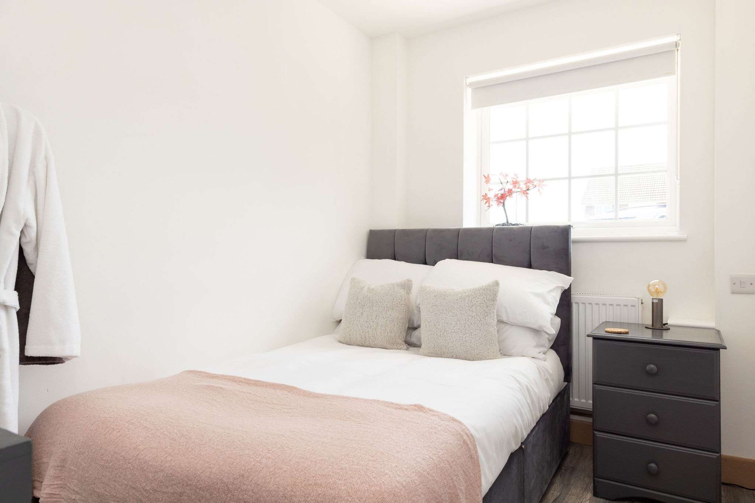A bedroom with a bed, bedside table, and a window with a view.