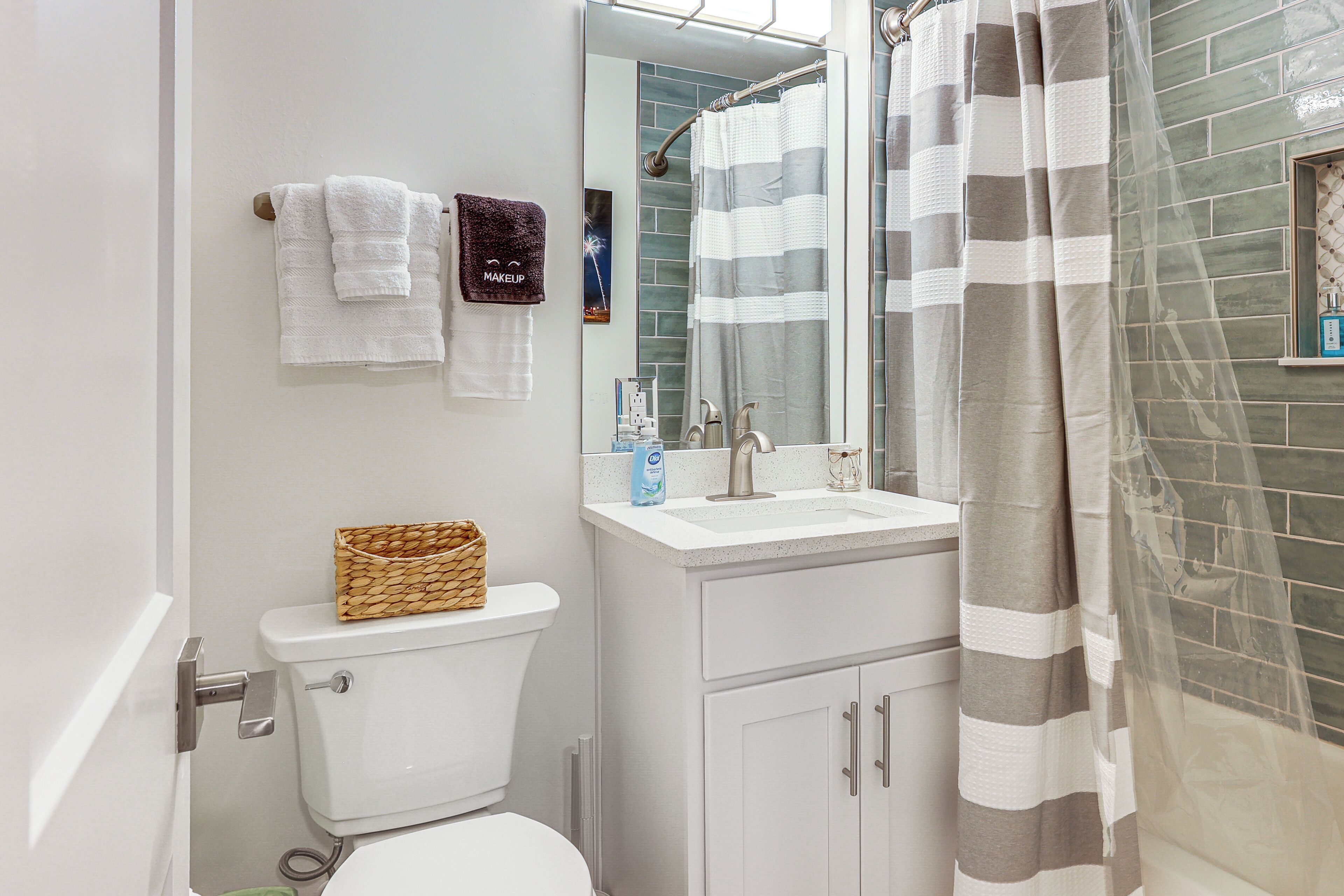 A bathroom with a toilet, a sink, a mirror, and a shower curtain.
