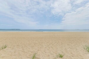 Una extensa playa de arena con cielo despejado y mar tranquilo.