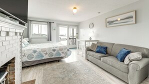 A bedroom with a bed, a grey sofa, a white table, and a window. - Beachfront Unit 24 in Old Orchard Beach (Old Orchard Beach)