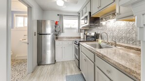 A modern kitchen with stainless steel appliances, white cabinets, and a granite countertop. - Beachfront Unit 24 in Old Orchard Beach (Old Orchard Beach)