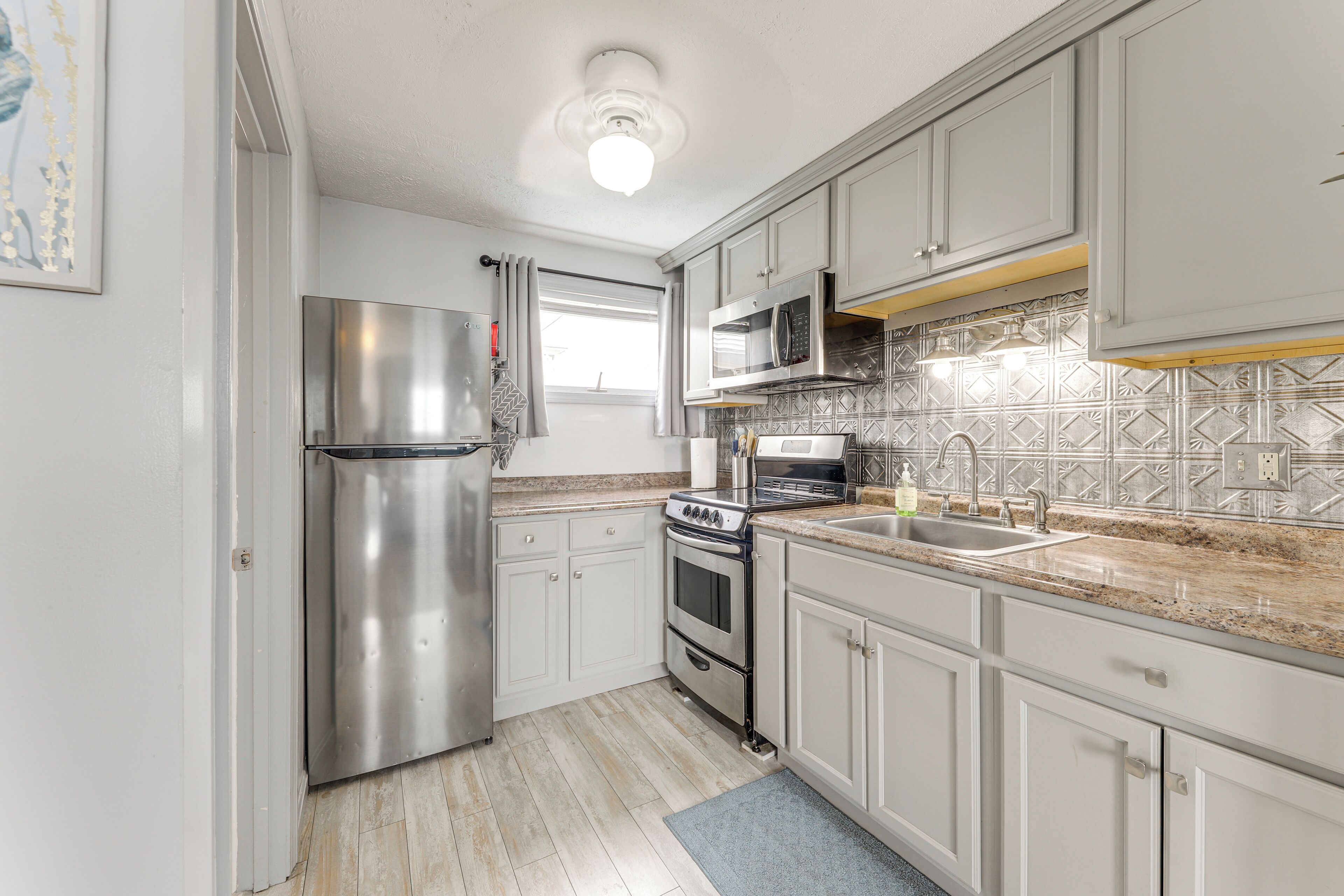 A kitchen with white cabinets, stainless steel appliances, and a patterned backsplash.