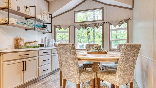 Un comedor con una mesa de madera, cuatro sillas tapizadas y un centro de mesa decorativo.