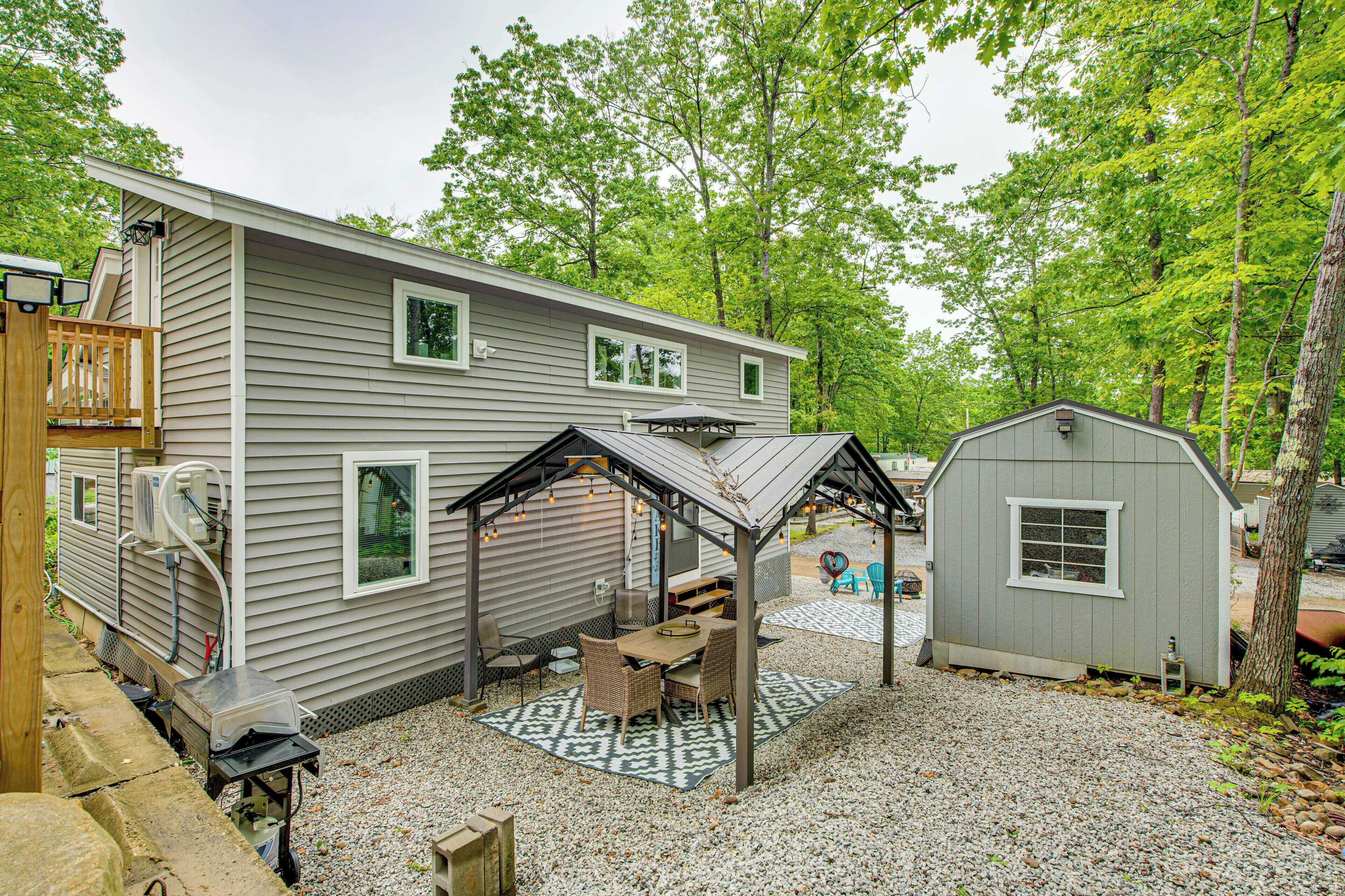 A mobile home with a covered patio, outdoor seating, and a small shed.