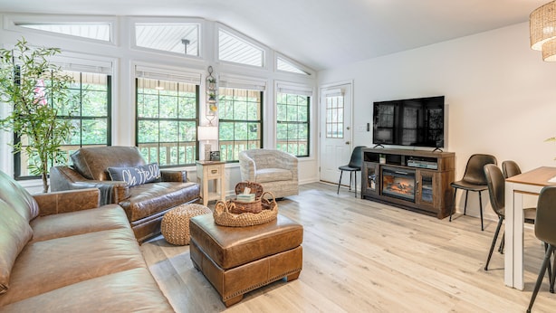 A spacious living room with a large sectional sofa, a fireplace, and a television. - 5 Mi to Dtwn Hiawassee: Creek-front Home w/ Deck (Hiawassee)