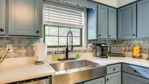 A kitchen with a stainless steel sink, a window with blinds, and a coffee maker on the counter. - 5 Mi to Dtwn Hiawassee: Creek-front Home w/ Deck (Hiawassee)