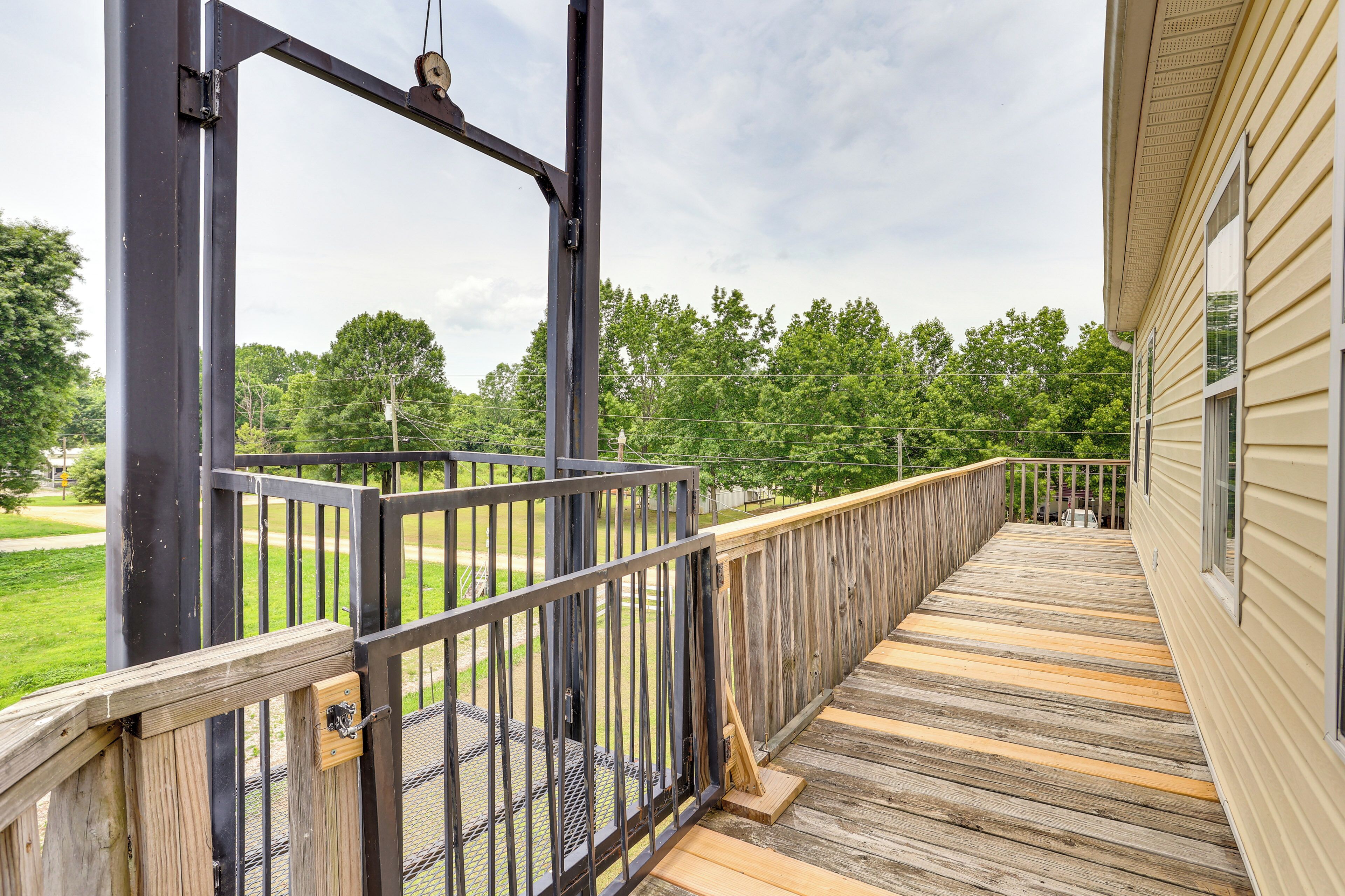 A wooden deck with a metal railing, leading to a building with beige siding.