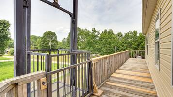 A wooden deck with a metal railing, leading to a building with beige siding.