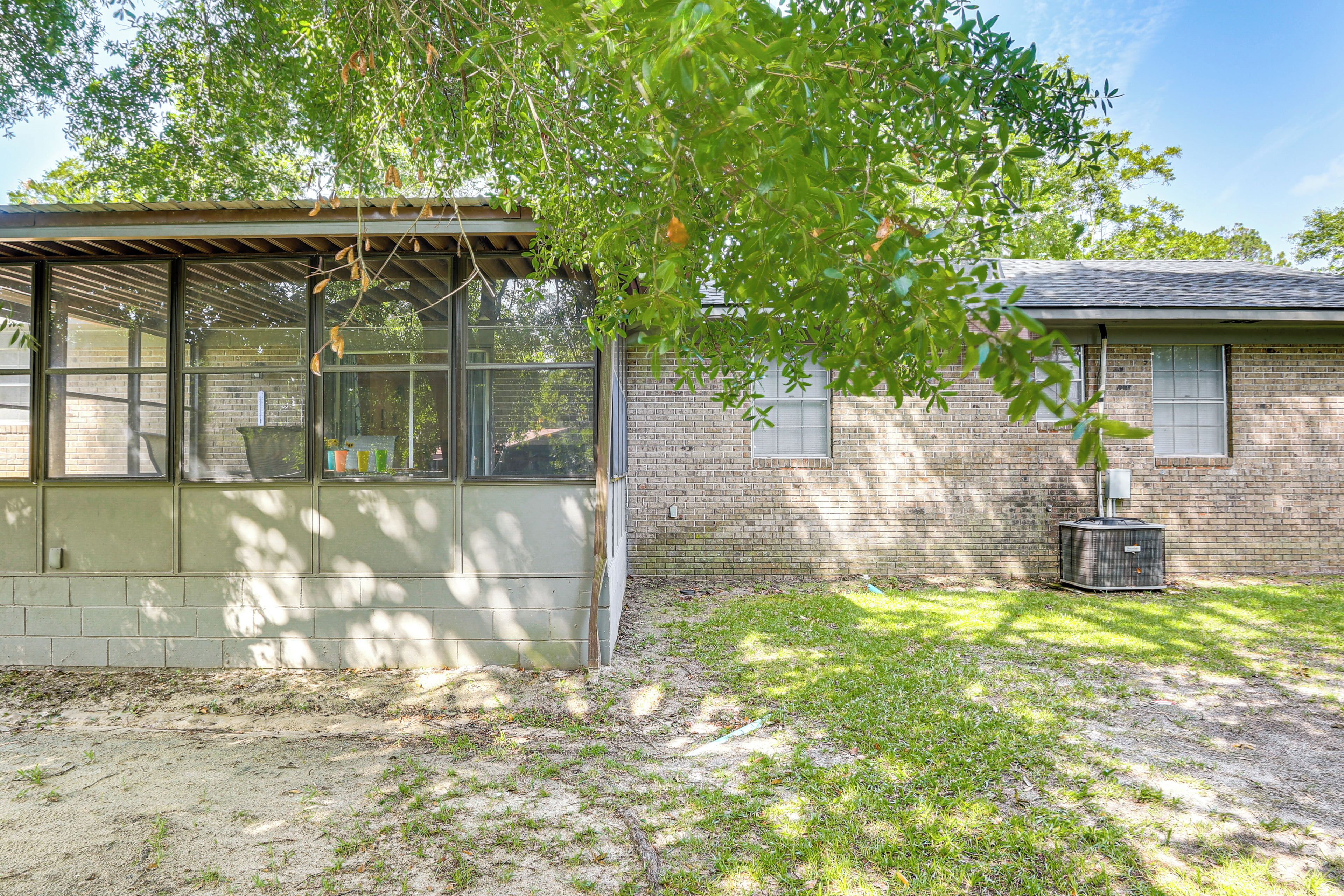 A single-story brick building with a covered patio area, a small garden, and a utility shed.