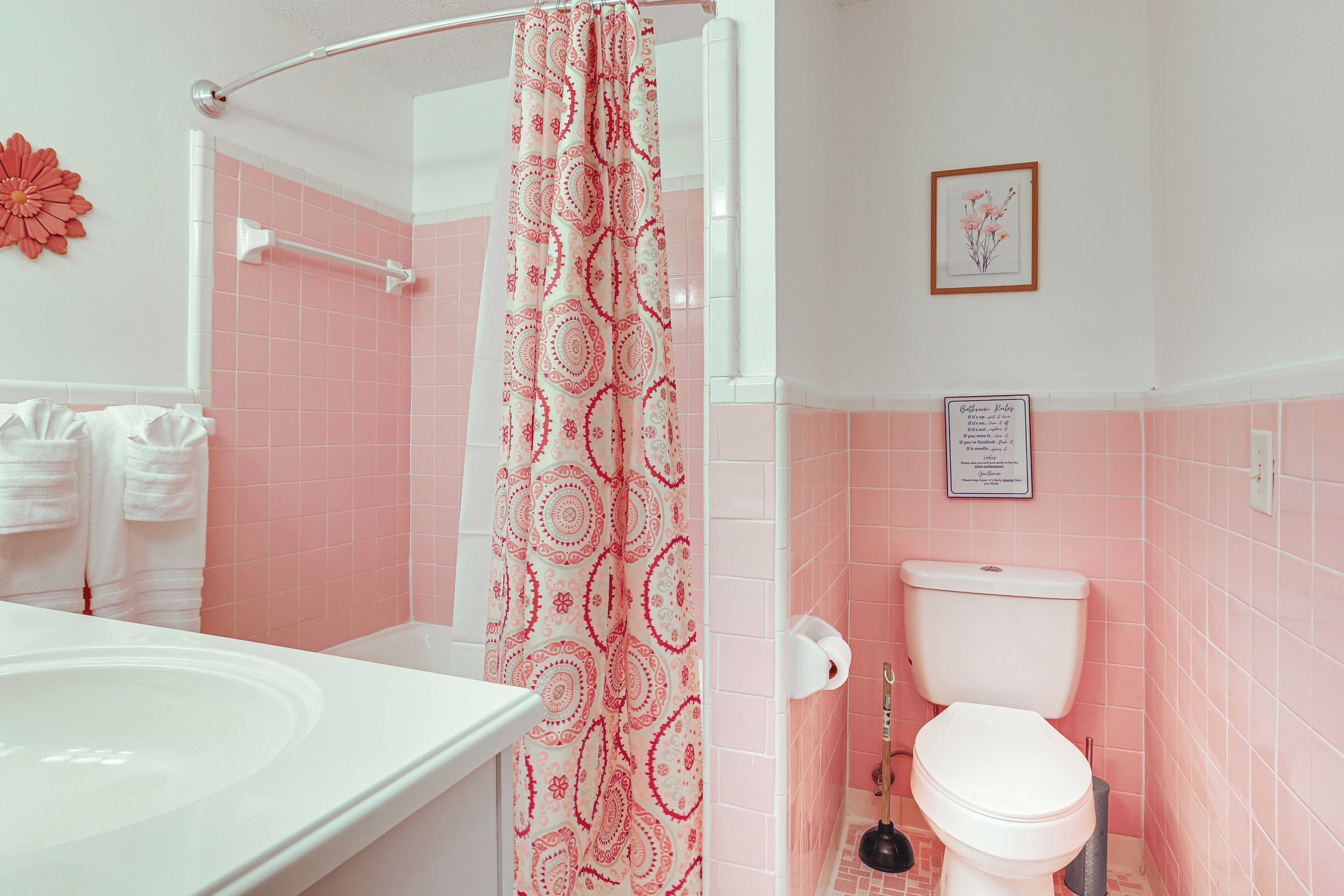 Een badkamer met een wit bad, een toilet en een douchegordijn met een paisley dessin.