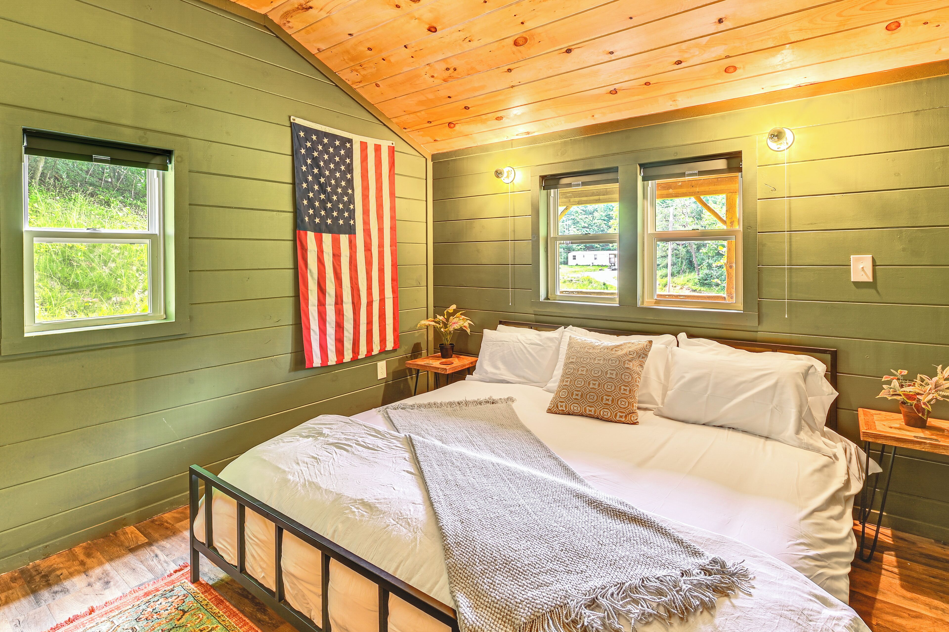 A bedroom with a bed, a nightstand, a lamp, and an American flag.