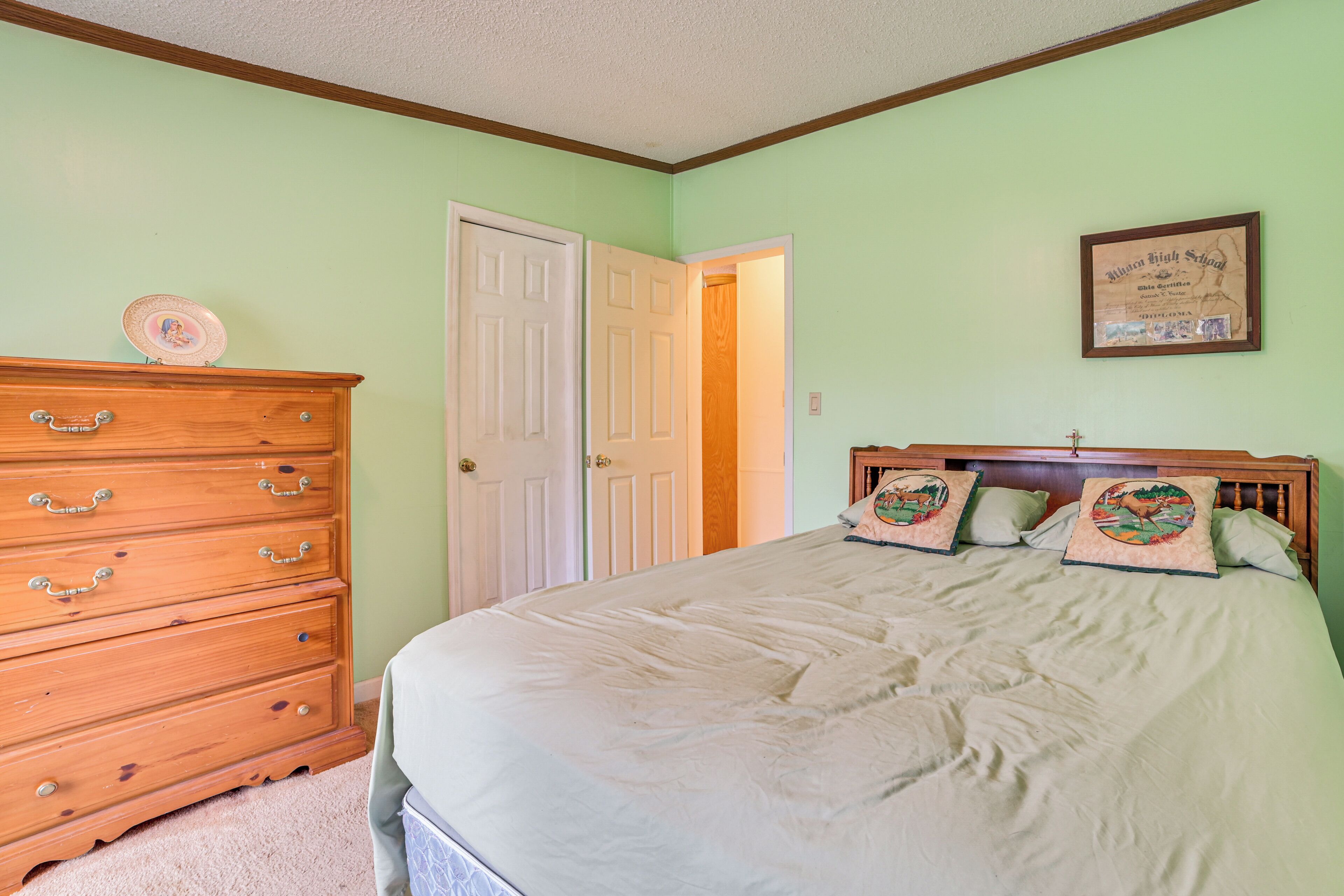 A bedroom with a bed, dresser, and a framed certificate on the wall.