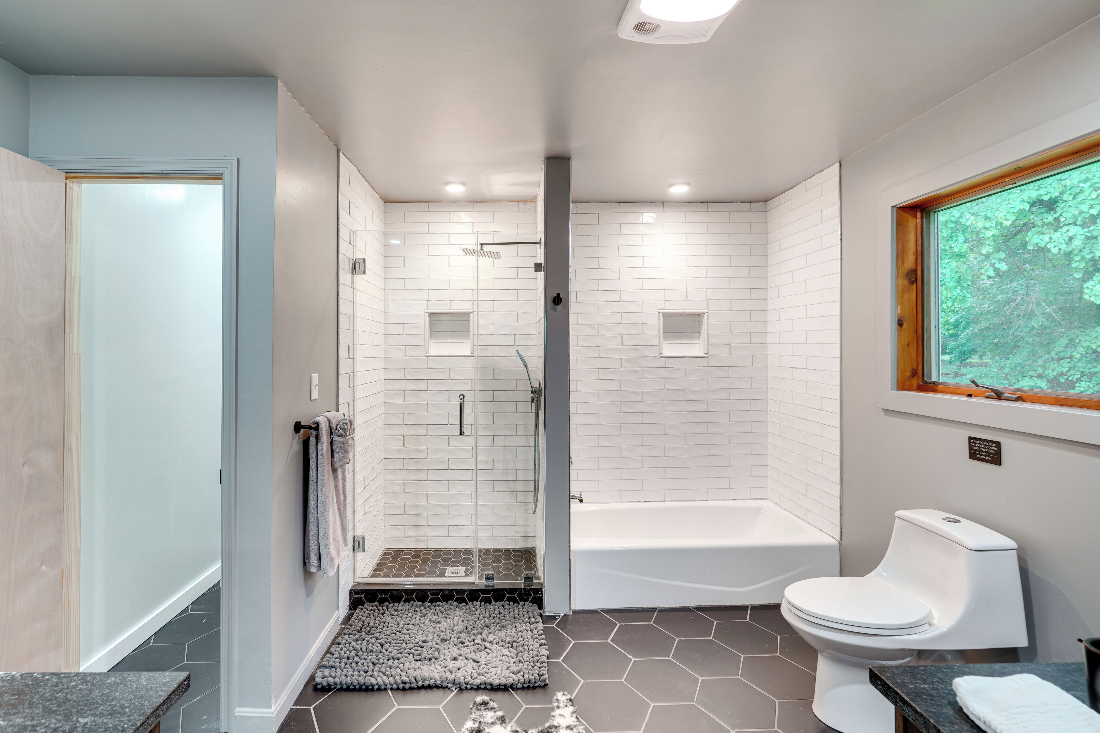 A modern bathroom with a shower, bathtub, and toilet.