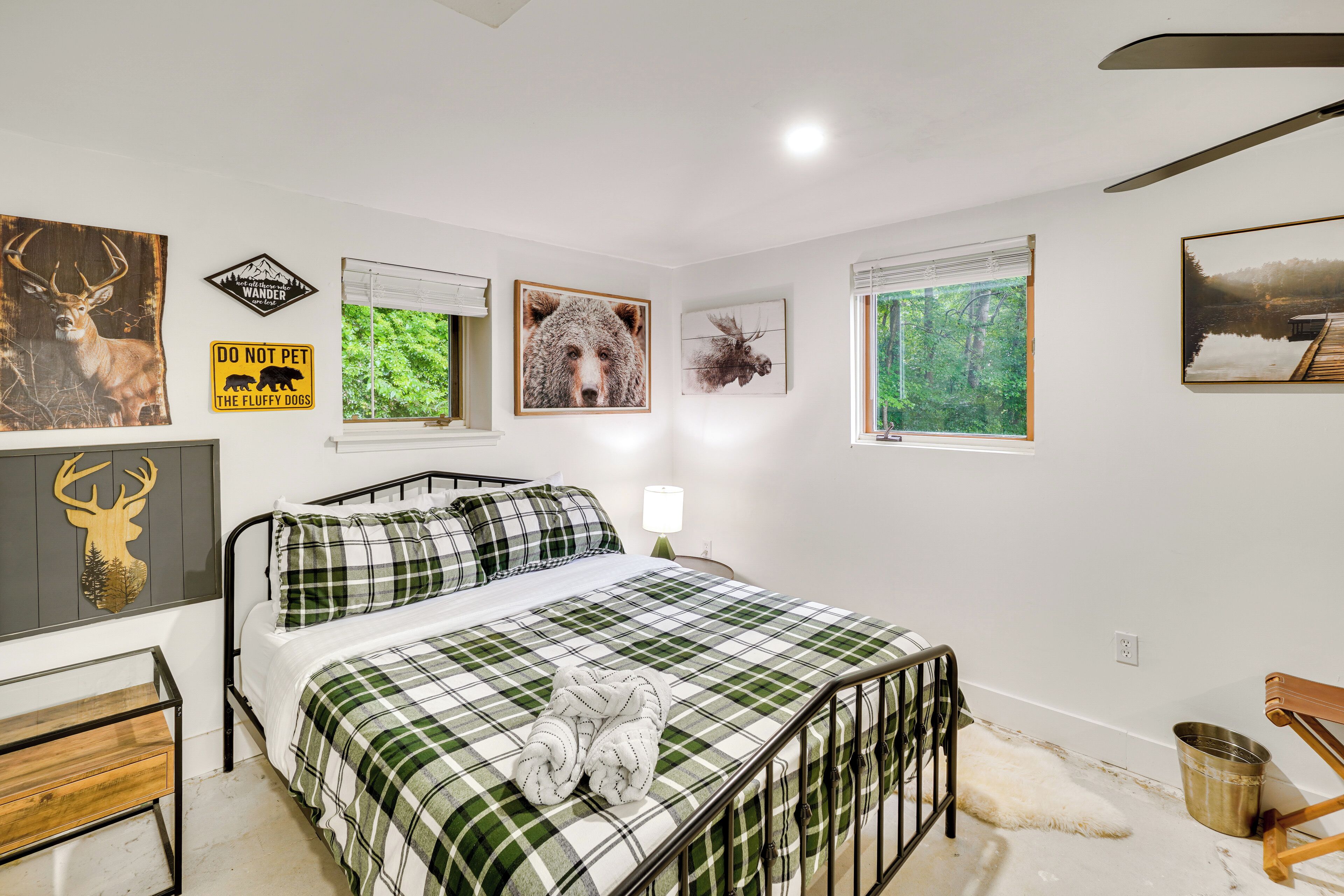 A bedroom with a bed, a bedside table, a lamp, and a window with a view of trees.
